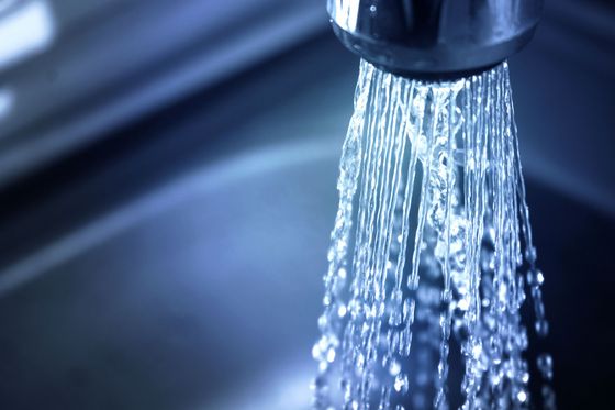 Water flowing from a chrome kitchen faucet into a dark sink.