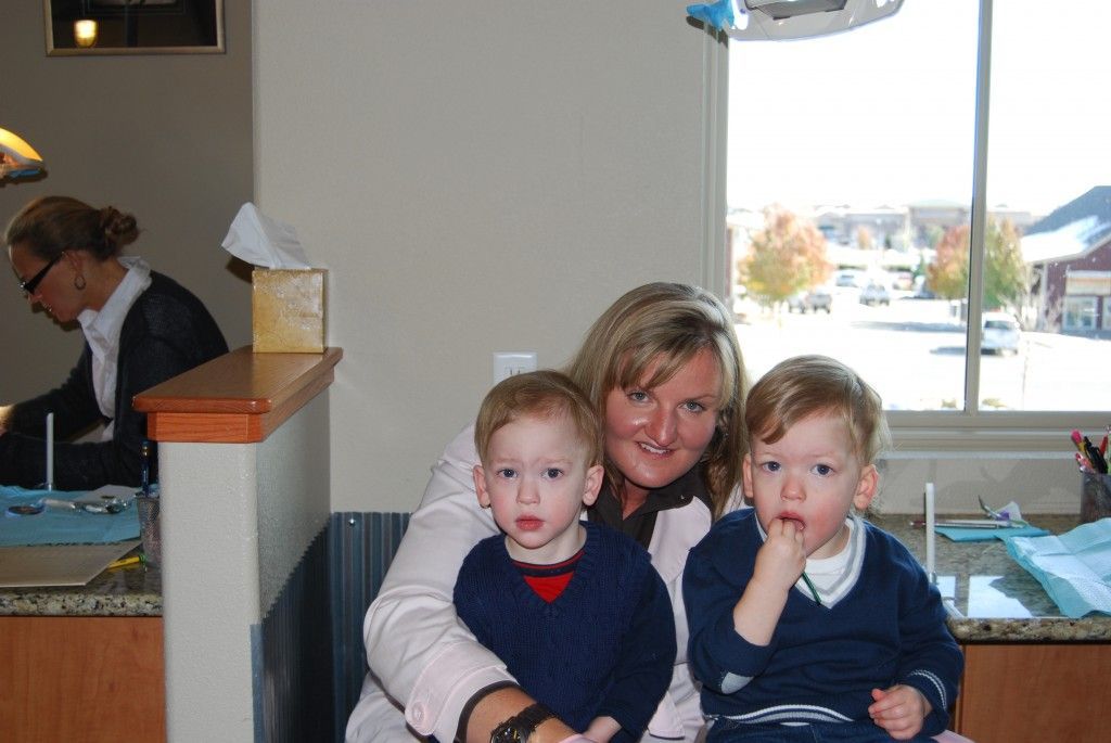 Woman sitting with two young children in a café, with a windowed waterfront view behind them
