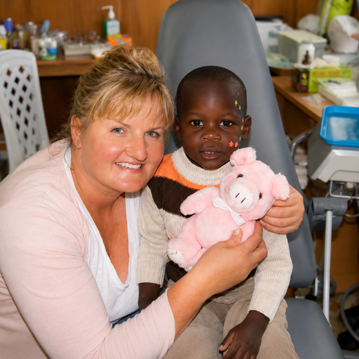 Woman holding a child with a pink stuffed animal in a cozy indoor setting