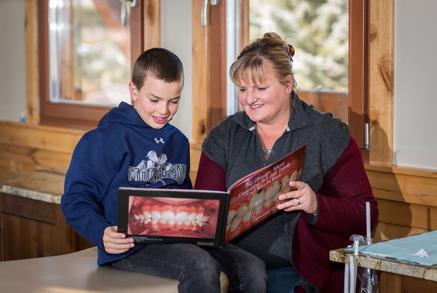 Woman and boy reading a photo album together on a wooden bench indoors