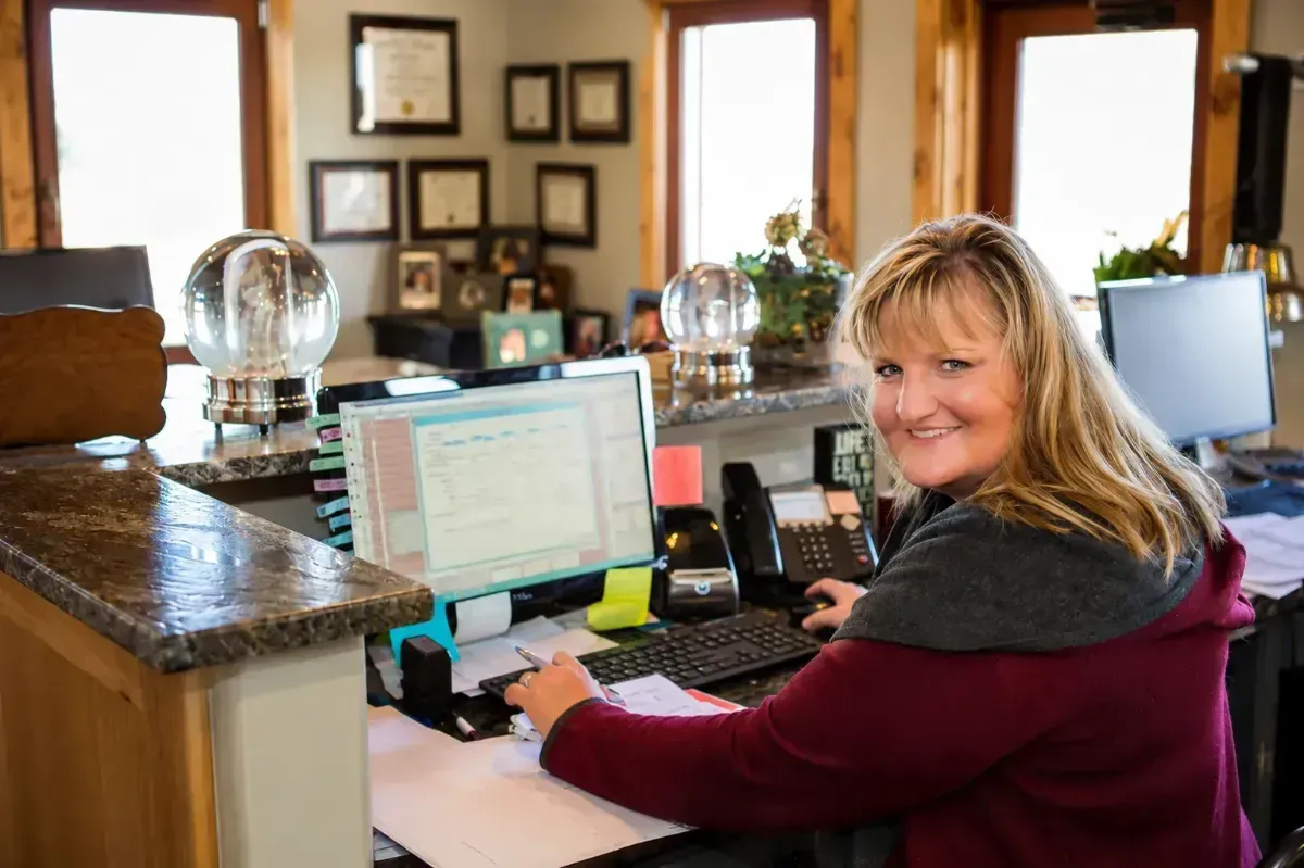 Woman smiling at a reception desk with a computer in an office lobby