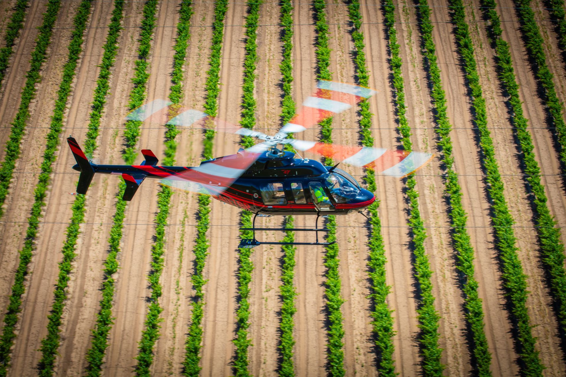 A helicopter is flying over a lush green field.