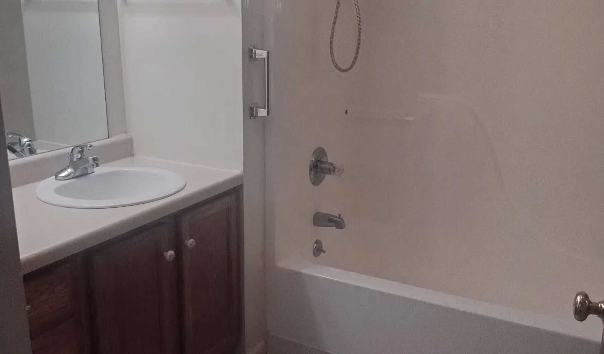 Bathroom with white sink, dark wood vanity, and beige bathtub with shower fixture.