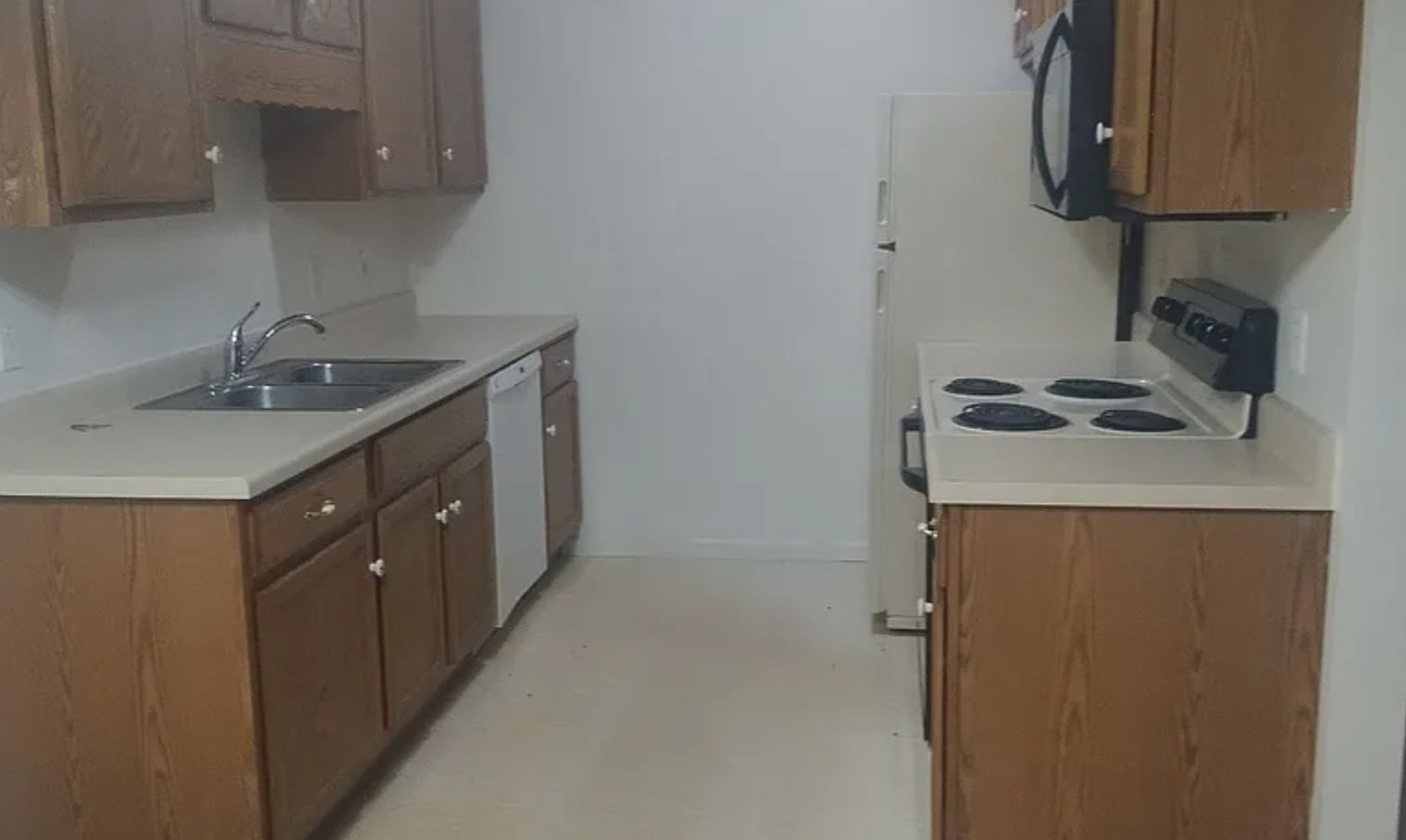 Small kitchen with wood cabinets, white countertops, and a white stove on the right.