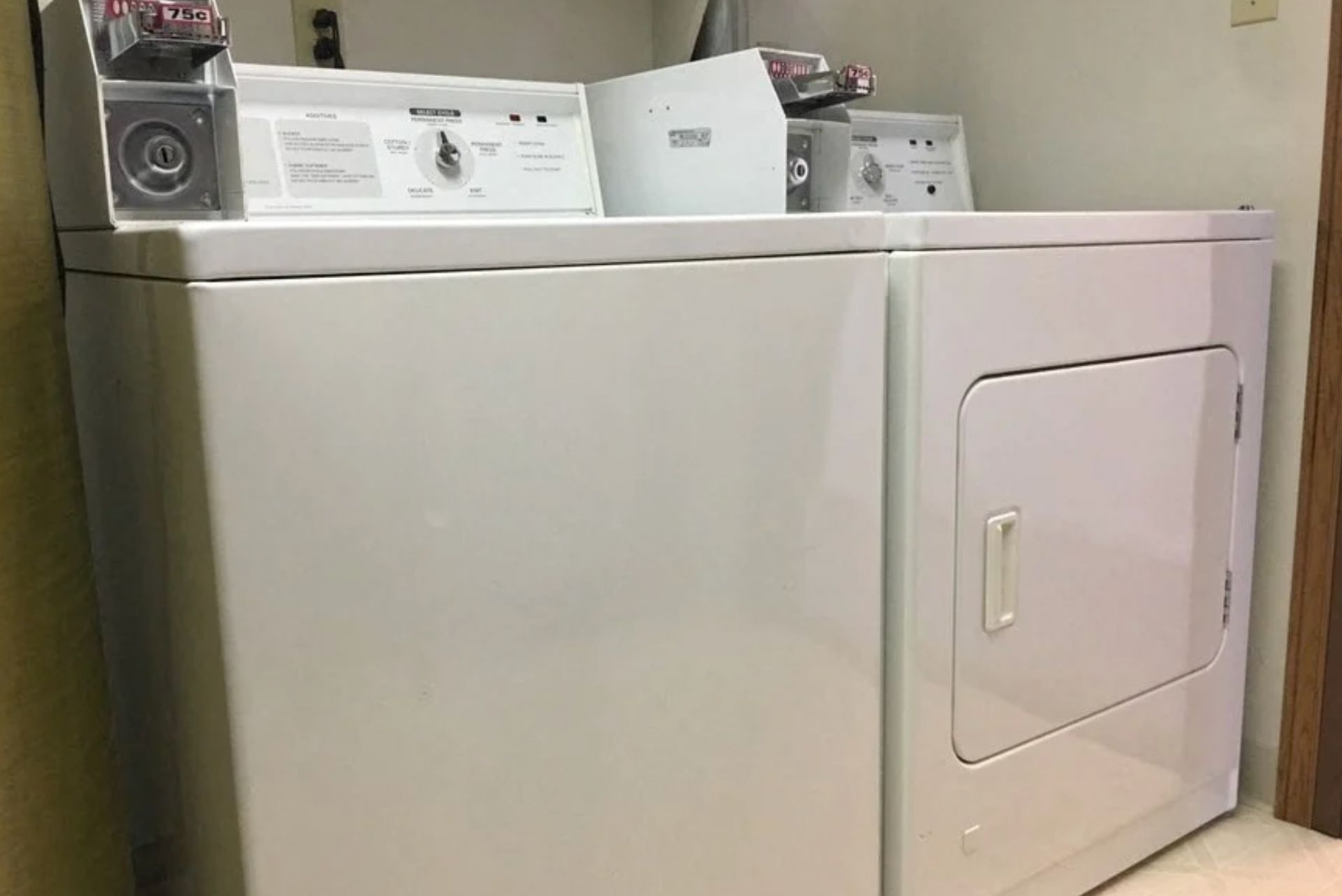 White front-loading dryer in a laundry room beside a matching washer.