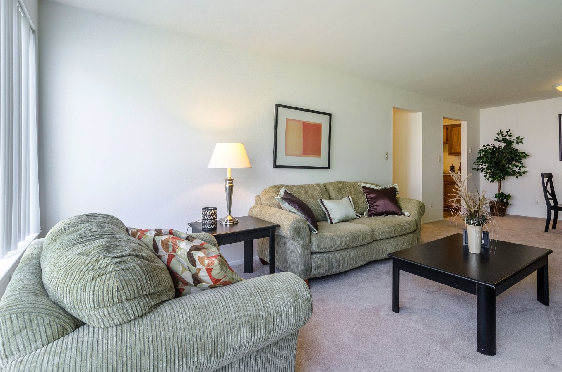 Bright living room with green armchairs, gray sofa, floor lamp, coffee table, and potted plant.