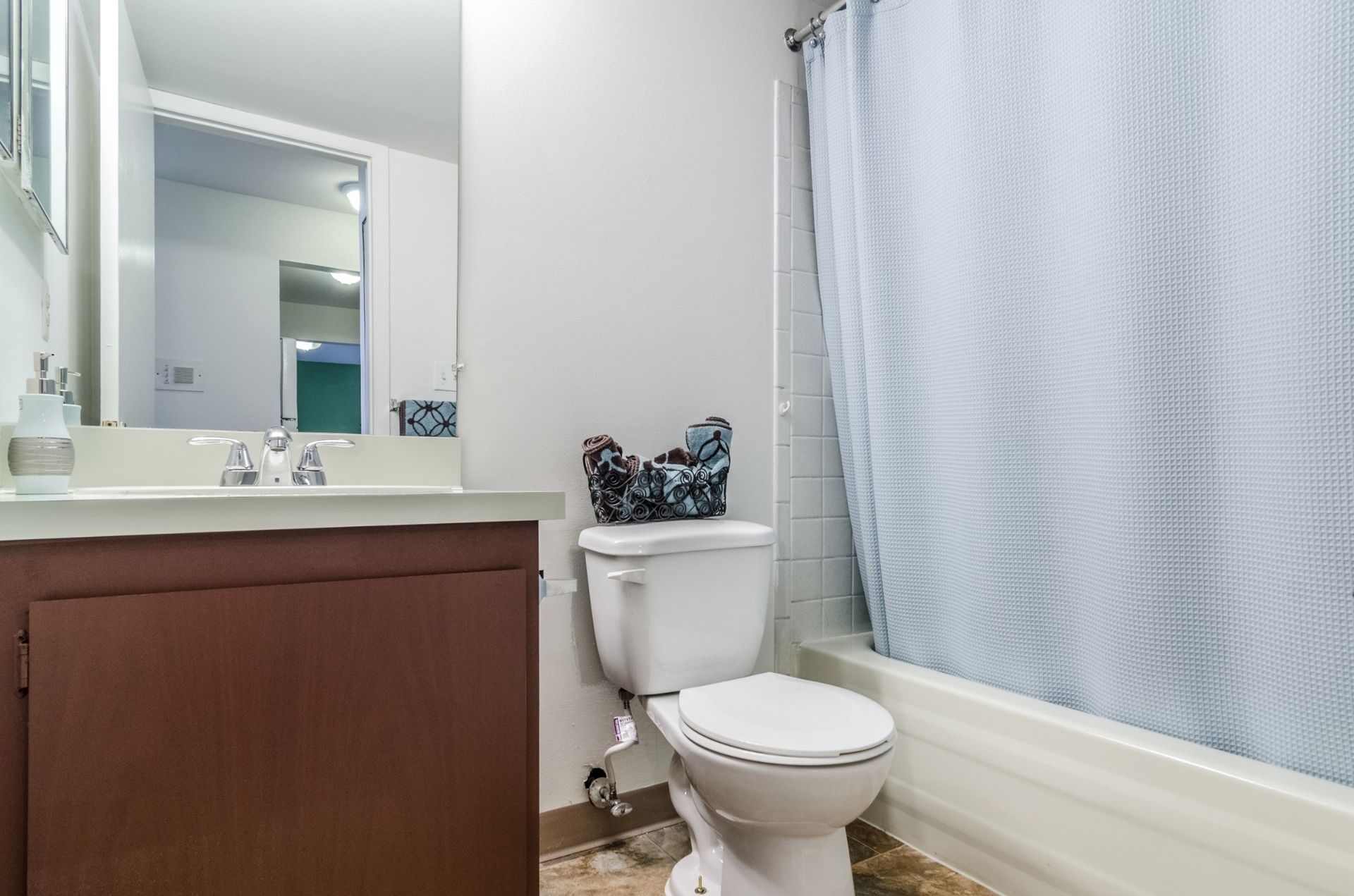 Small bathroom with vanity, mirror, toilet, and bathtub with shower curtain