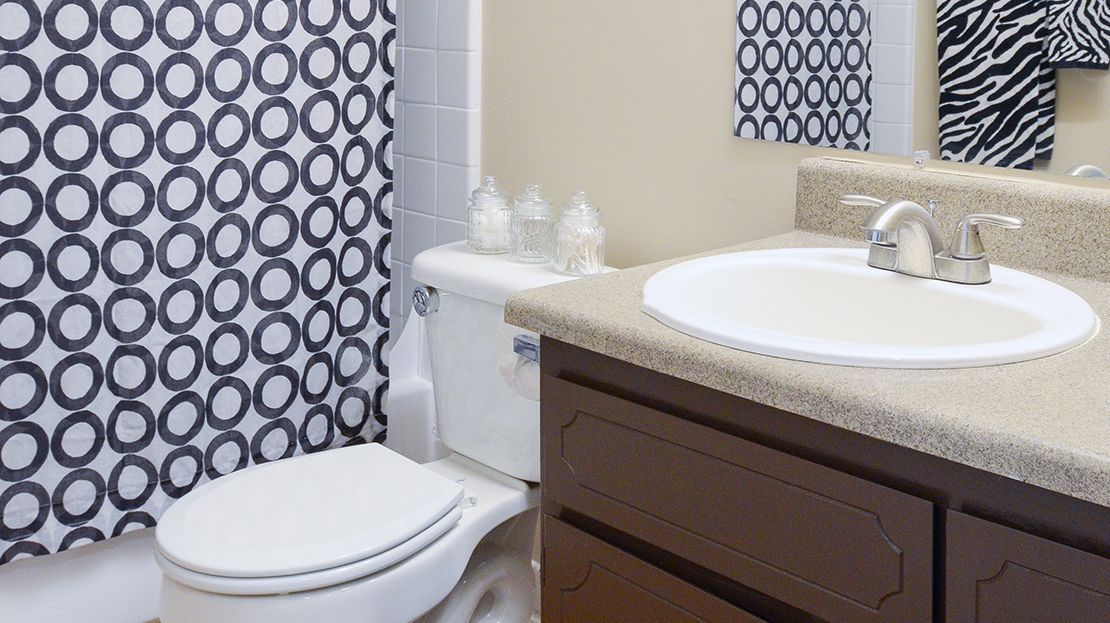 Modern bathroom with patterned shower curtain, toilet, and sink vanity