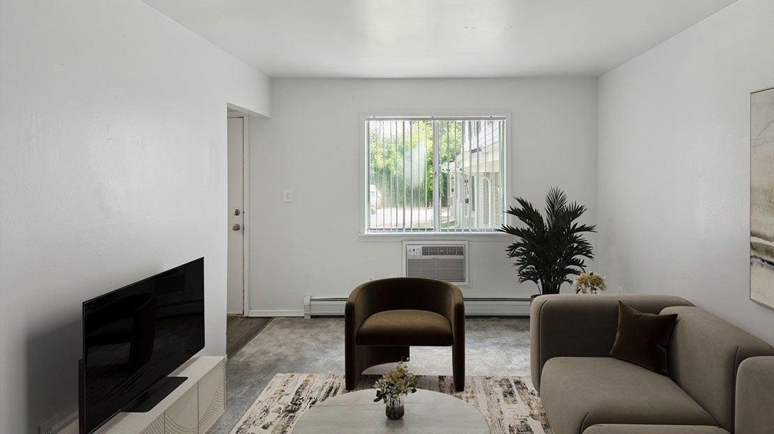 Minimalist living room with gray sofa, brown chair, TV, and window with blinds