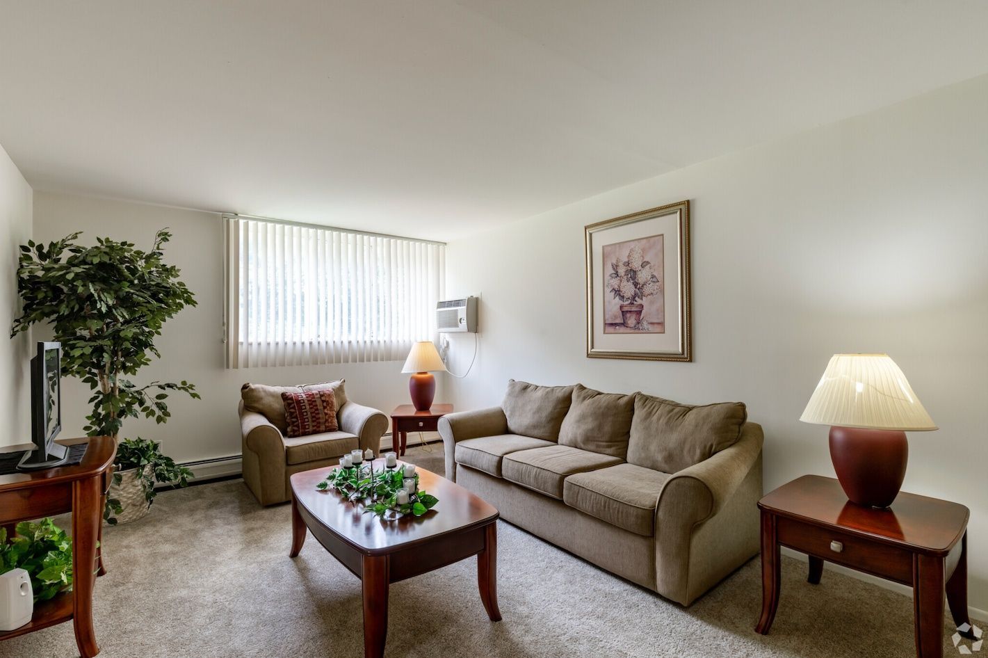Bright living room with beige sofa, armchair, coffee table, lamps, and large window with blinds