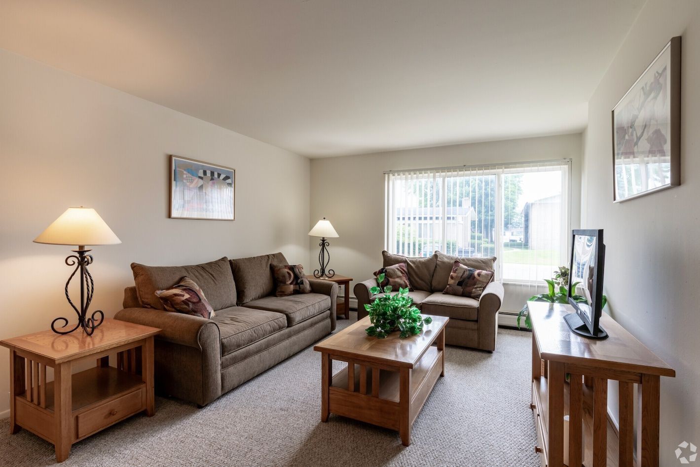 Living room with brown sofas, coffee table, lamps, TV, and large window