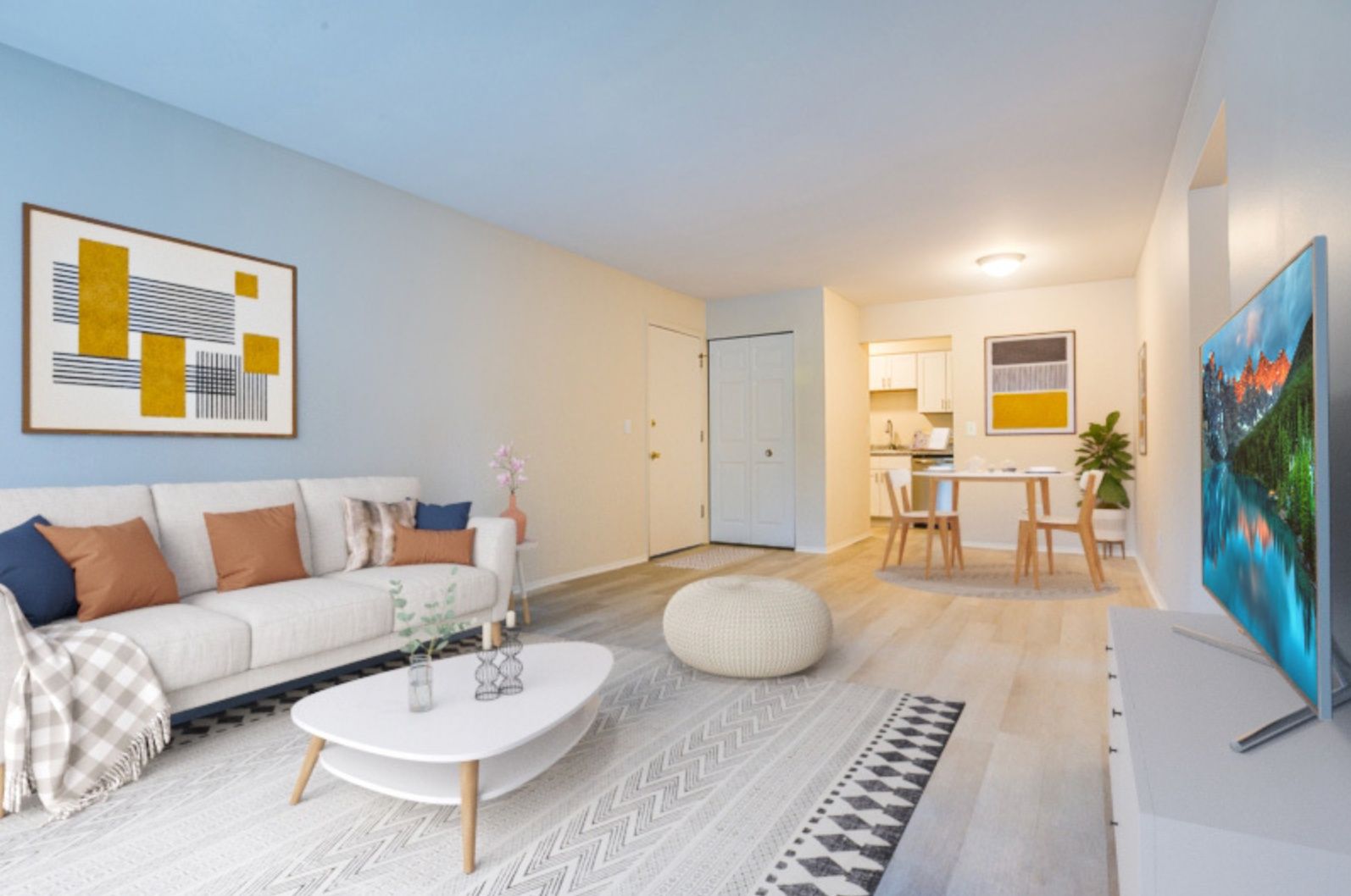 Bright modern living room with sofa, coffee table, dining nook, and wall art in white tones