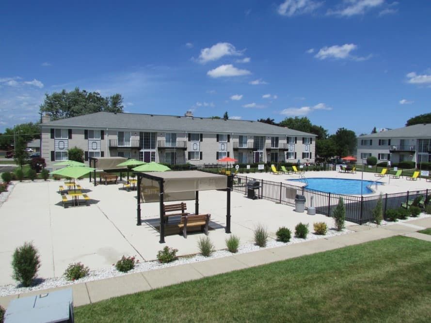 Apartment complex courtyard with pool, cabanas, and picnic tables on a sunny day