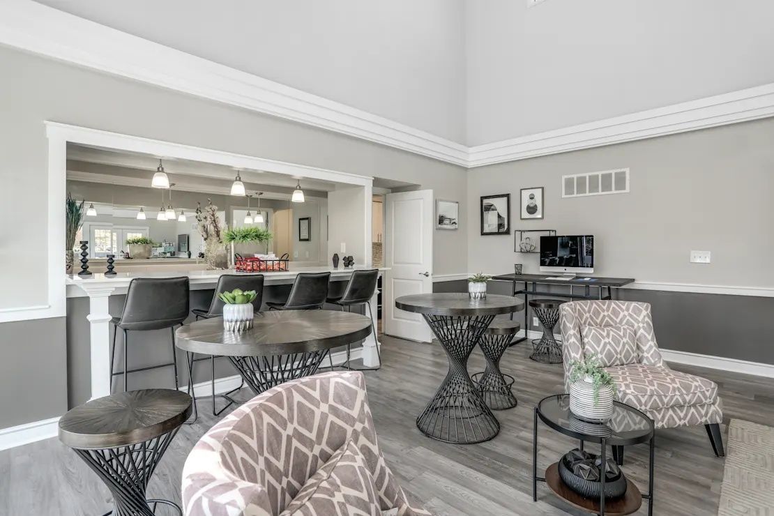 Bright modern living room with gray walls, patterned chairs, and a view into a kitchen area