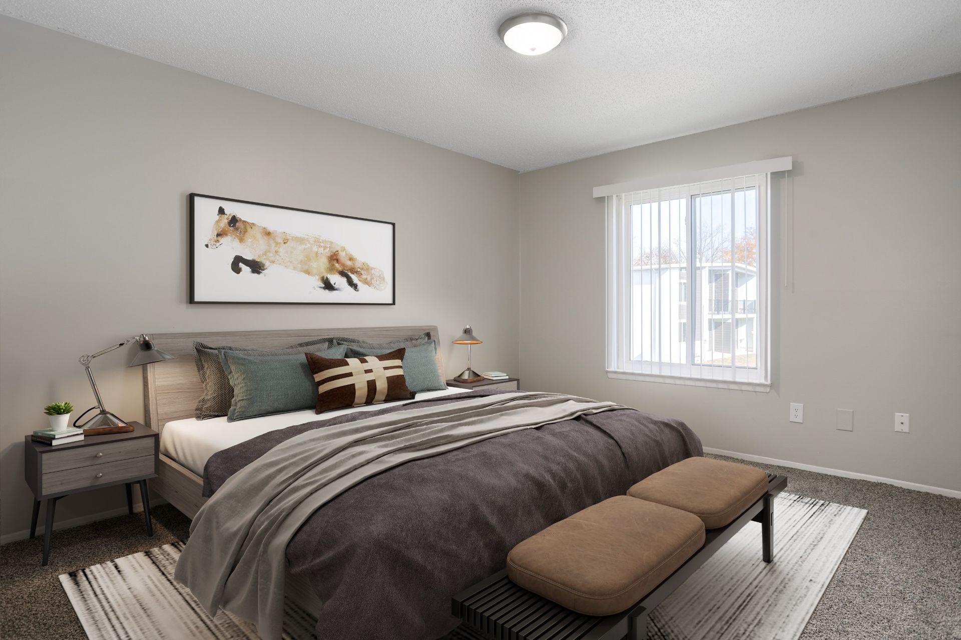 Neutral bedroom with a bed, bench, nightstand, framed art, and a window with white curtains.