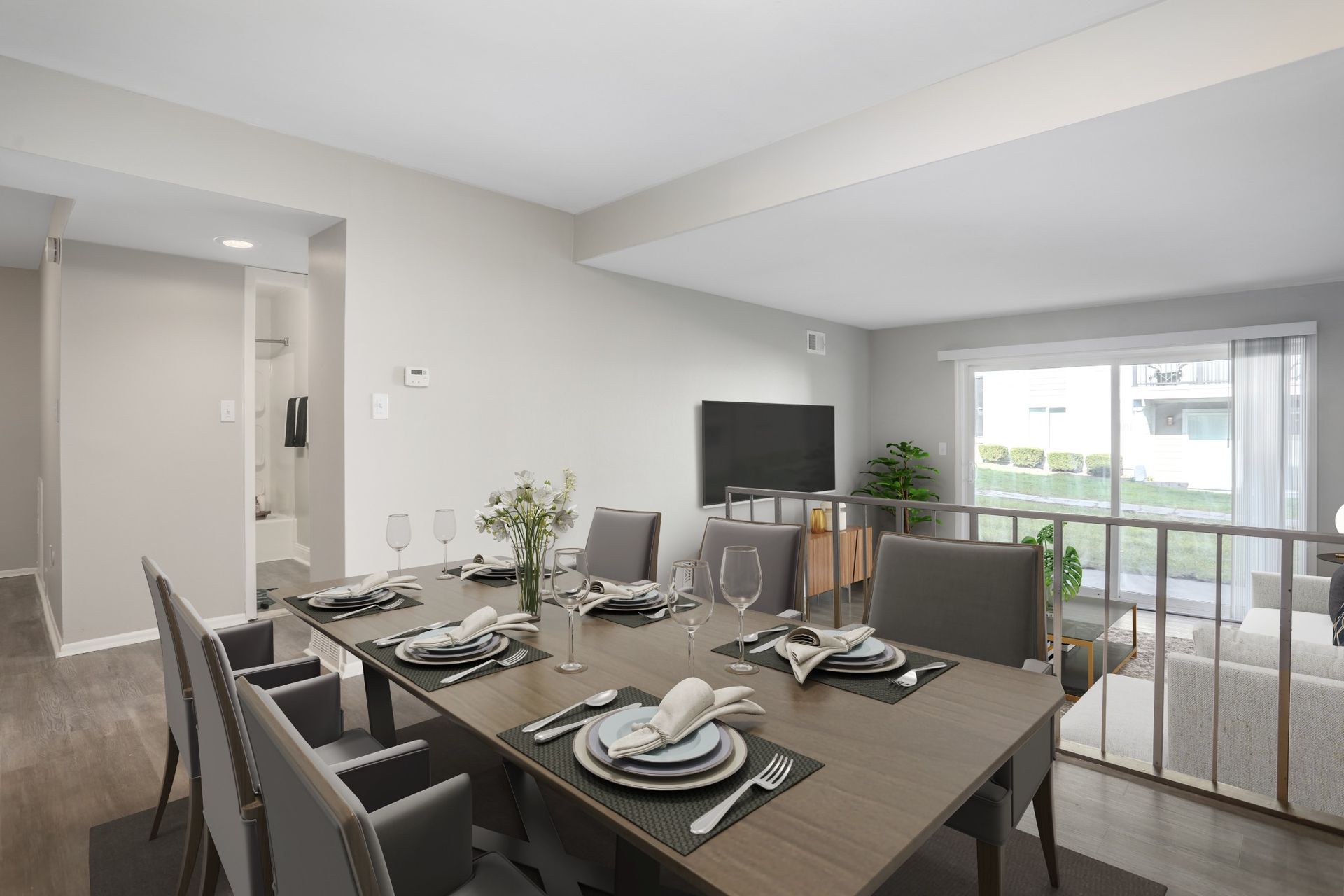 Modern dining room with set table, TV, and sliding doors to a balcony