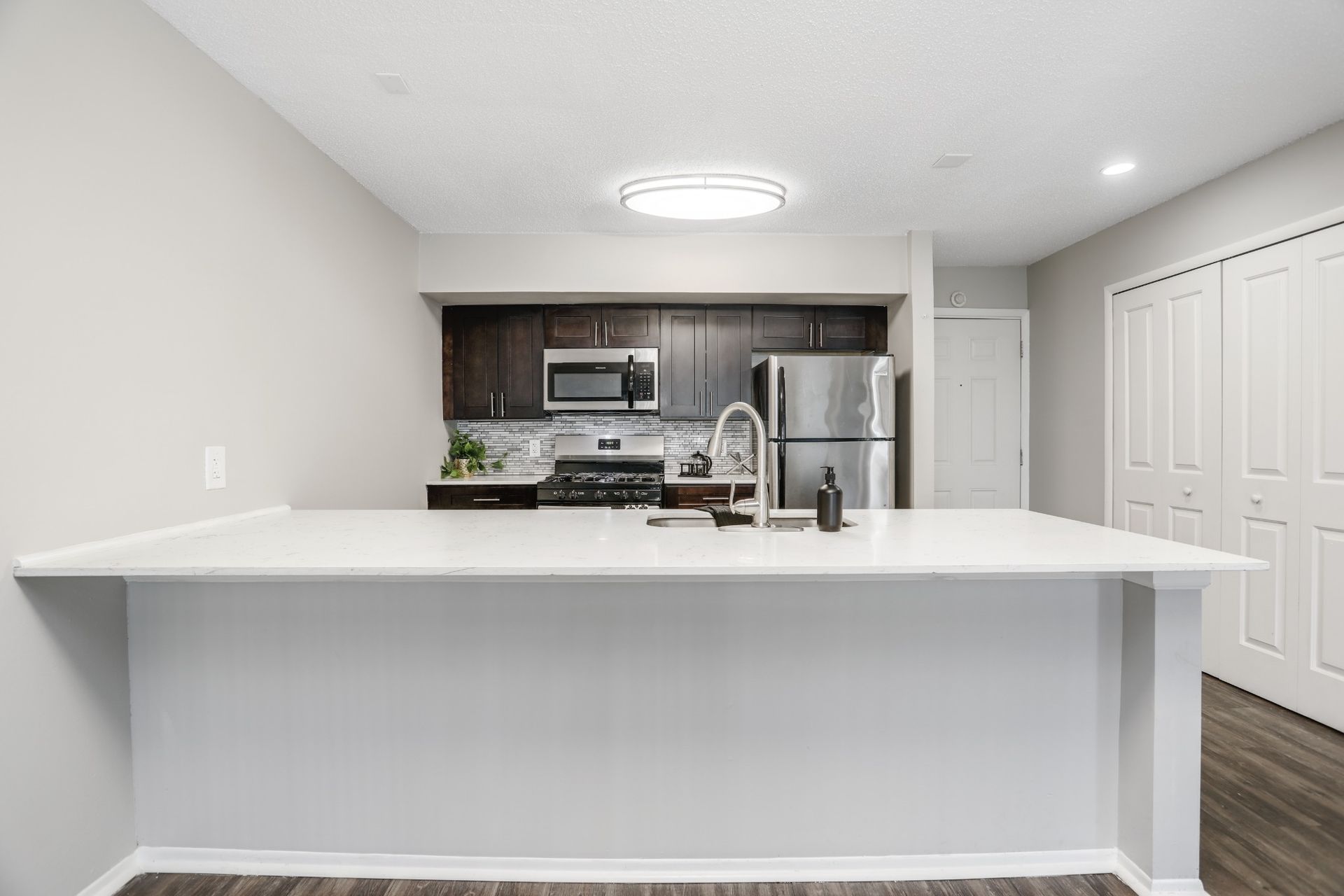 Bright modern kitchen with white island, stainless steel appliances, and recessed lighting