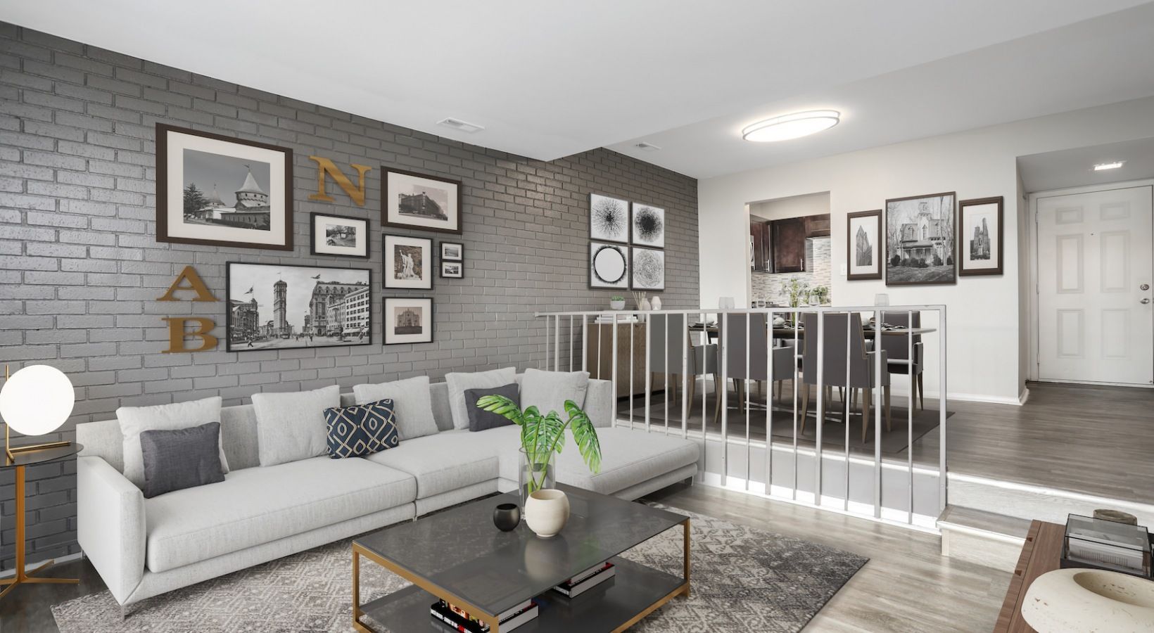 Modern gray living room with white sofa, gallery wall, coffee table, and staircase railing