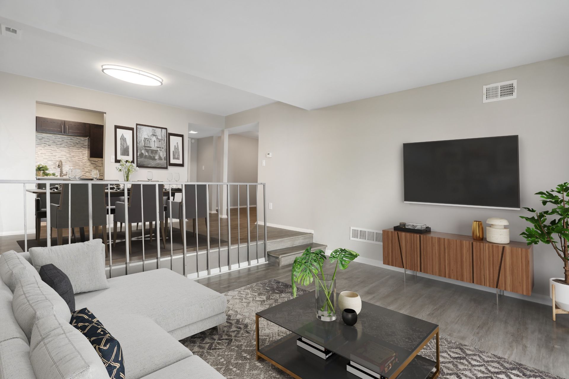 Modern gray living room with sofa, coffee table, wall art, and staircase railing