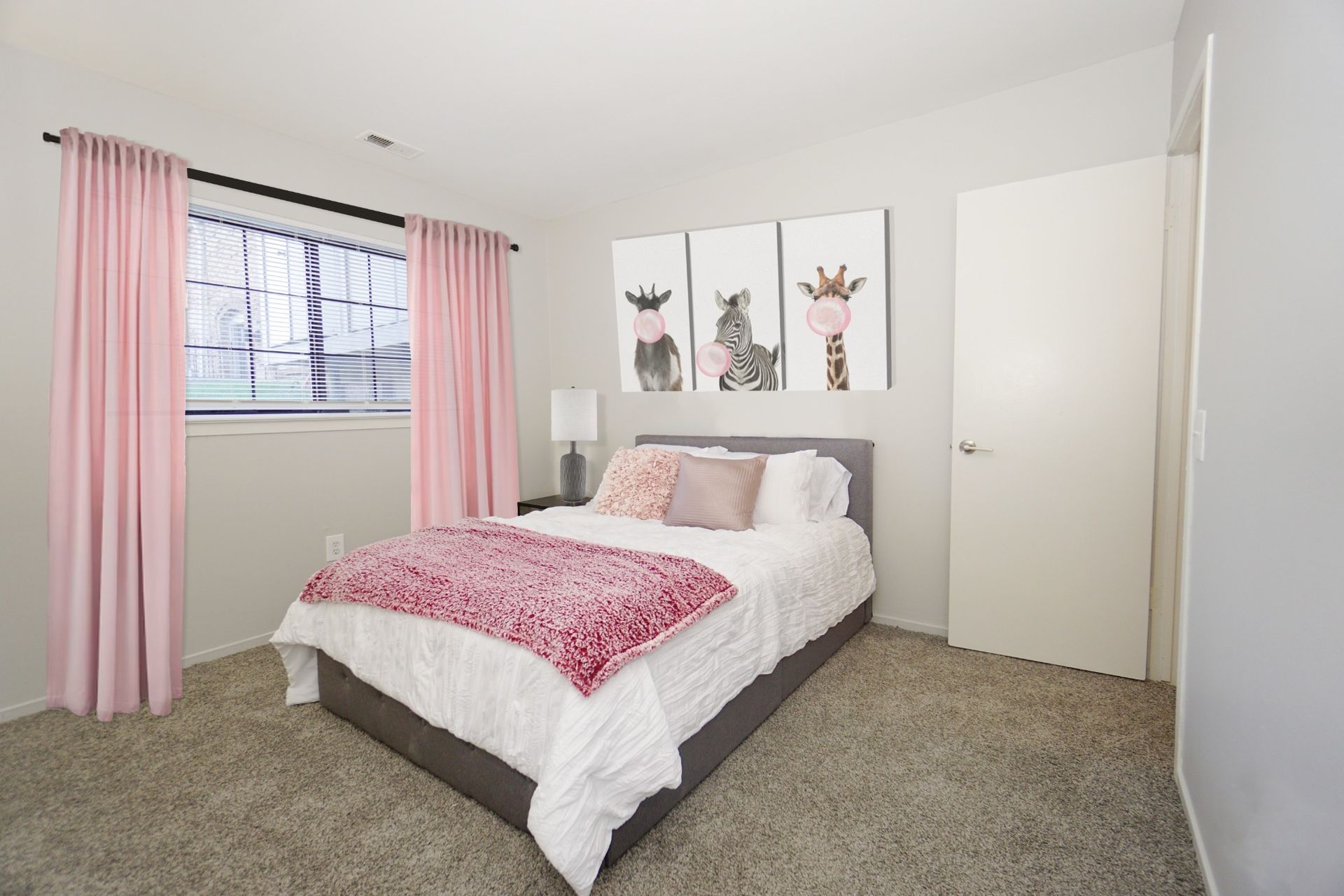 Bright bedroom with pink curtains, a bed with pink bedding, and three rabbit wall prints