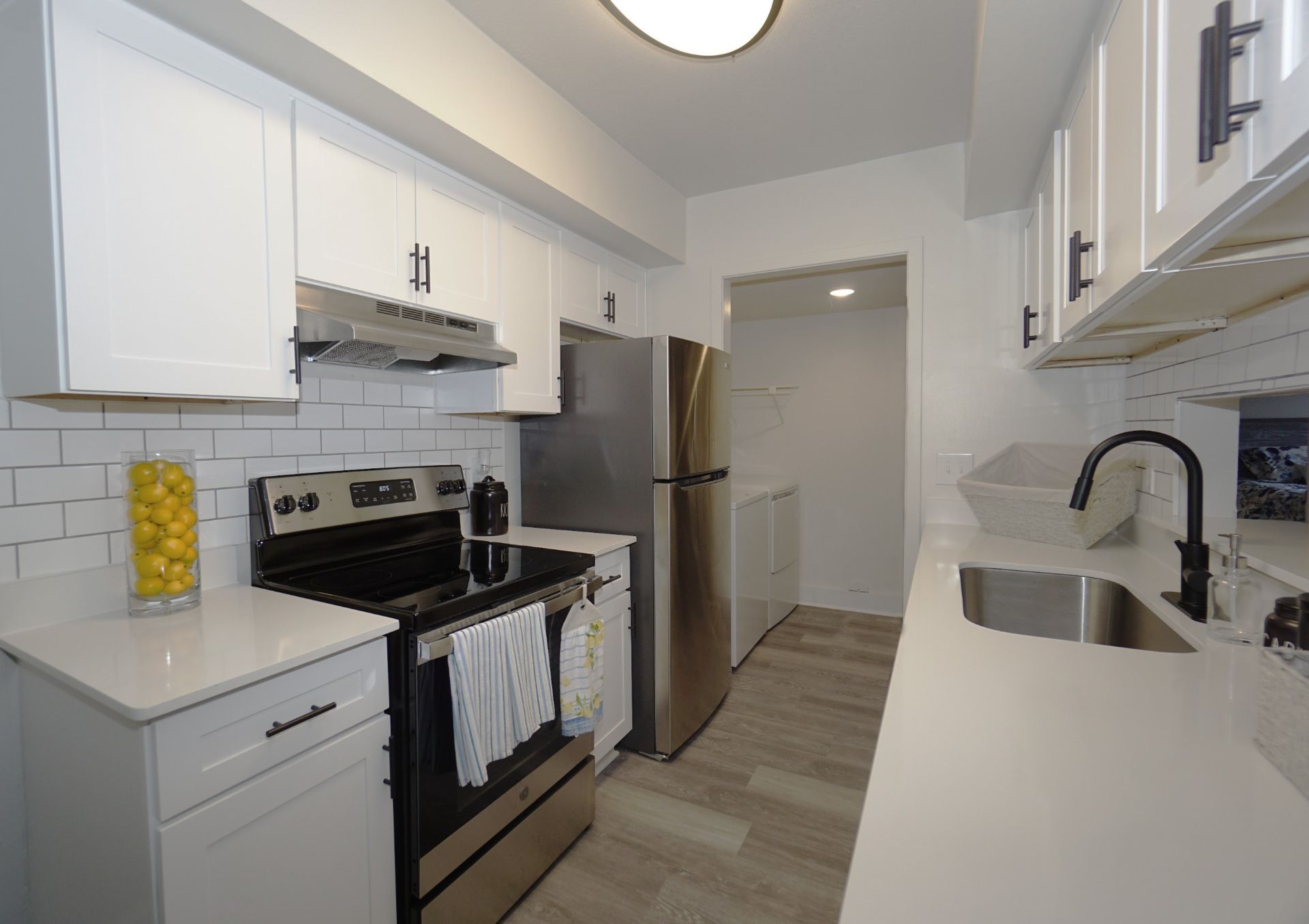 Bright modern kitchen with white cabinets, stainless steel appliances, and a black stove.