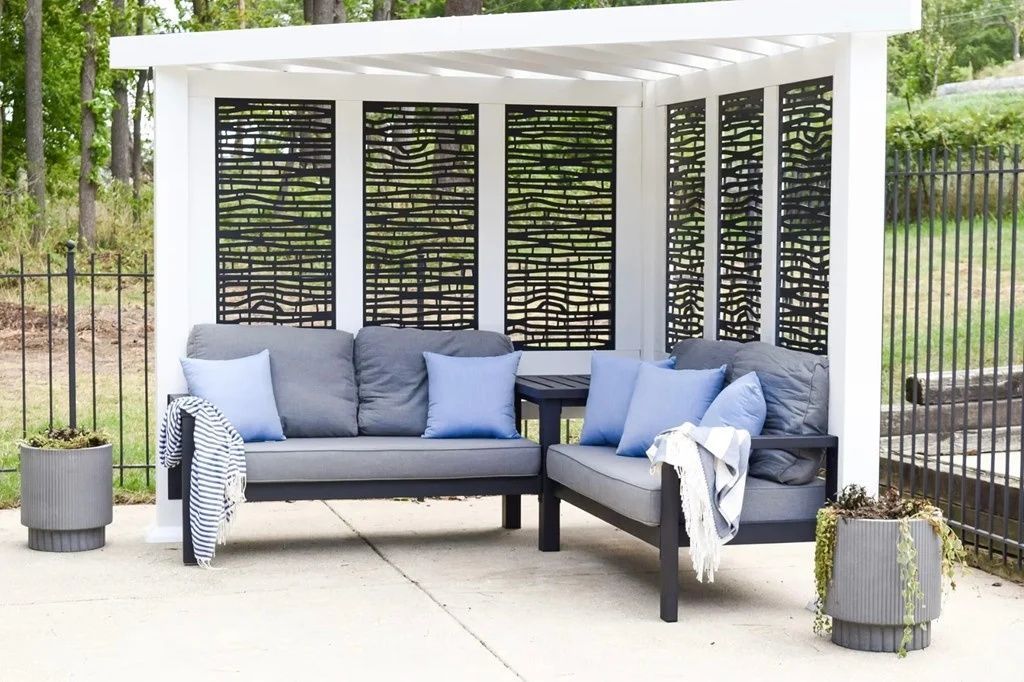 Outdoor patio lounge with gray sofa, blue pillows, white canopy, and potted plants