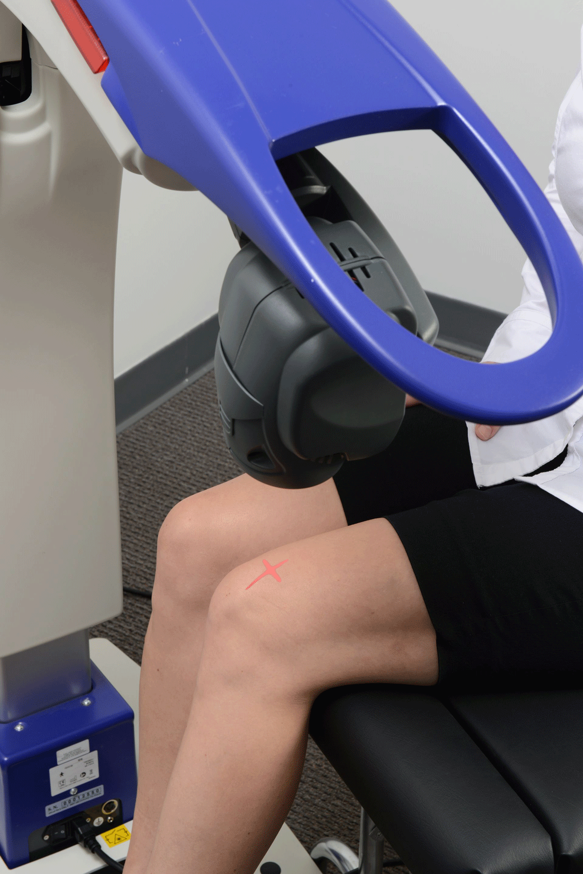 A woman is sitting in a chair with a blue device on her knee