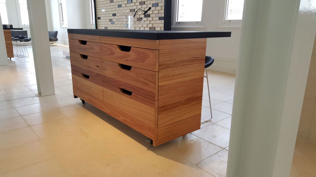 Wooden kitchen island with black countertop in a bright, tiled room