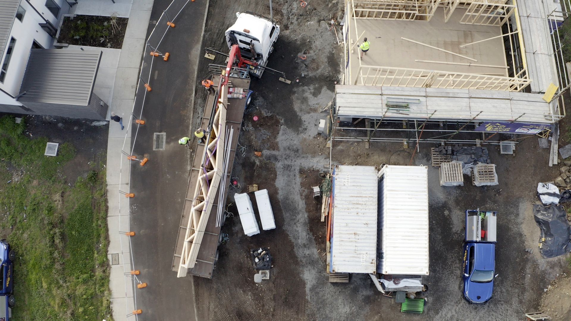 Aerial view of a fire truck with an extended ladder beside a damaged building and parked vehicles.