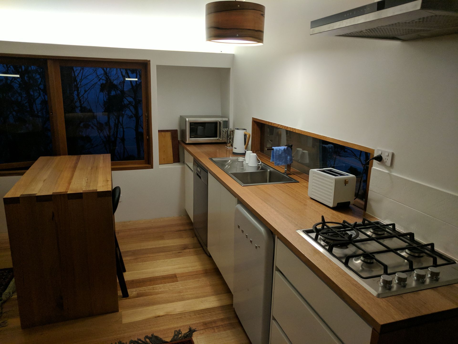 Modern kitchen with wooden counters, gas stove, microwave, and a dining table by the window
