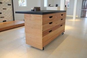 Wooden kitchen island on casters with black countertop in a bright room