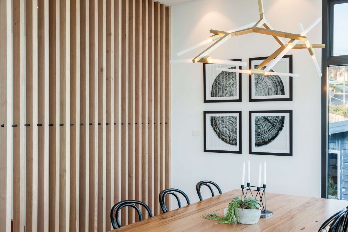 Modern dining room with wooden table, black chairs, wall art, and a geometric pendant light