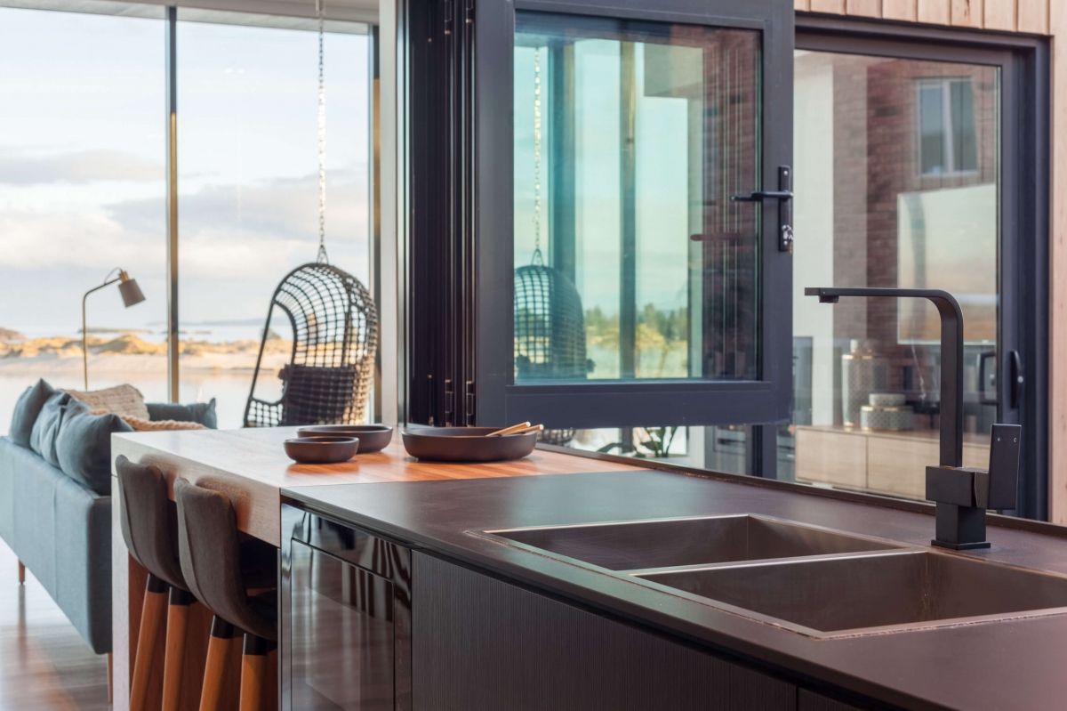 Modern kitchen with dark cabinets, island sink, and large windows overlooking a balcony and city view