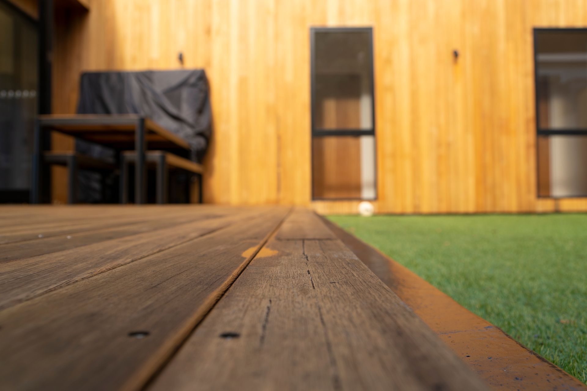 Low wooden walkway beside green turf in a wood-paneled indoor room