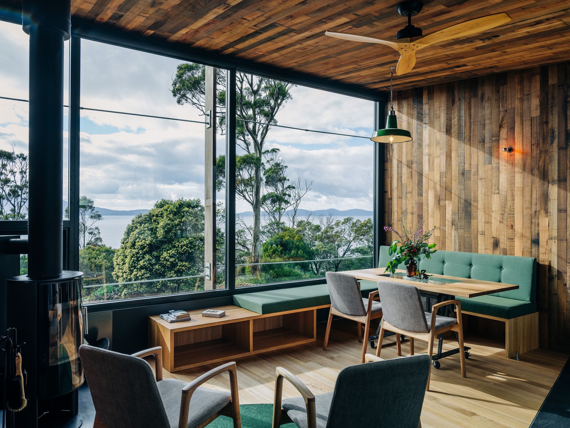 Cozy café seating by large windows with wood ceiling, green booth, and tables overlooking a city view