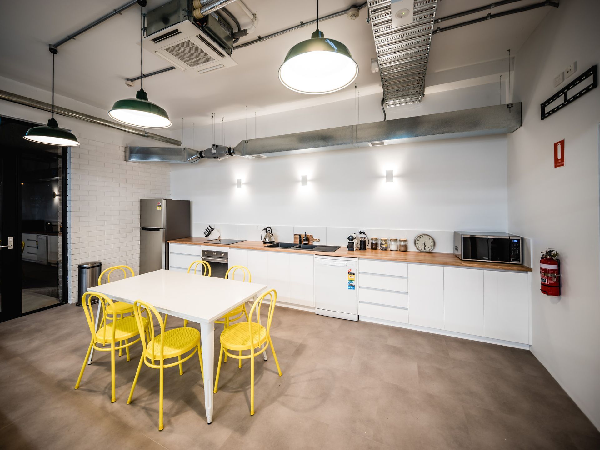Modern kitchen with white counters, yellow chairs, and hanging pendant lights