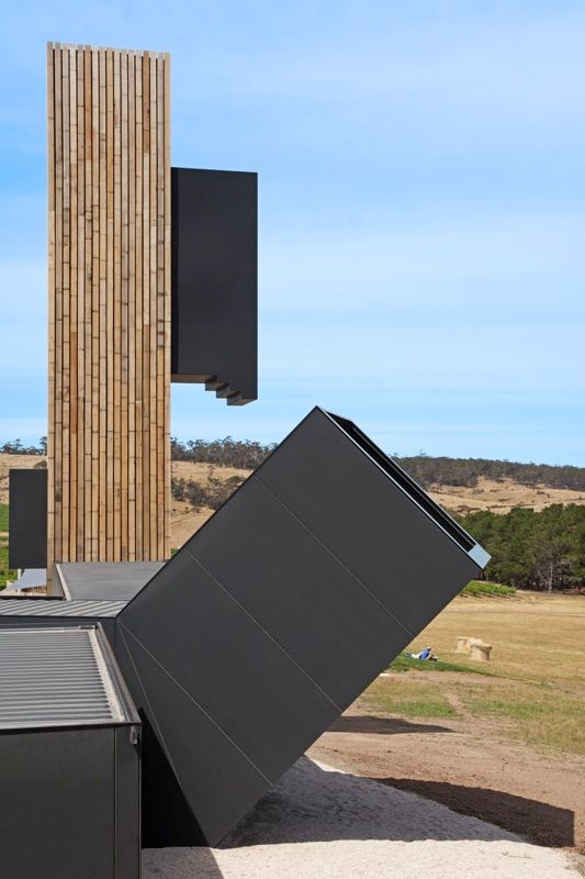 Solar panels and vertical wooden slats on a grassy field under a blue sky.