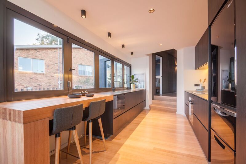 Sleek kitchen with wood floors, black cabinets, and wood counter.