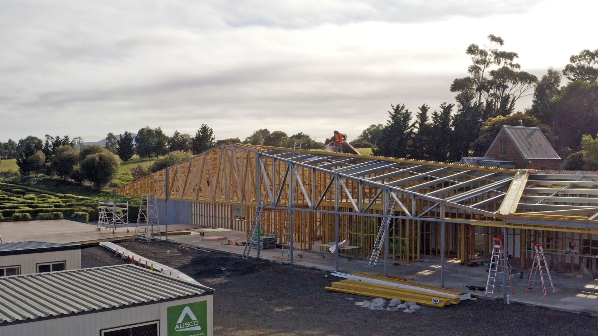 Partially built wooden house frame on a construction site under a cloudy sky