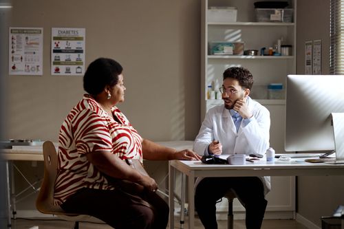 Doctor consulting with a patient across a desk in a clinic office