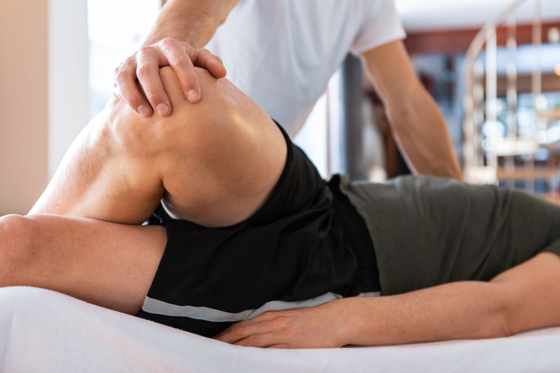 Hands-on physical therapy stretch on a patient lying on a table in a clinic.