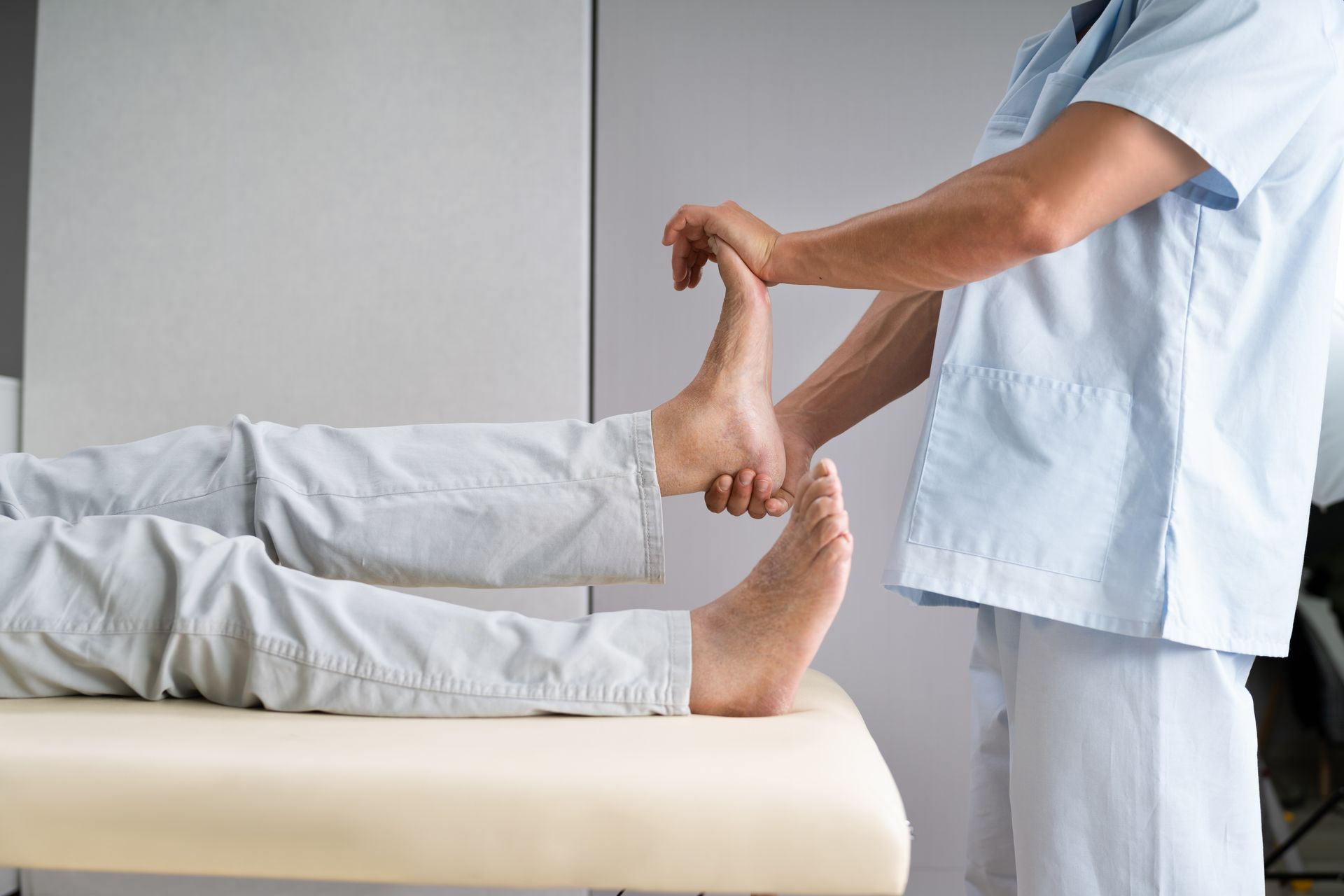 Clinician stretching a patient’s leg on a therapy table during a physical exam