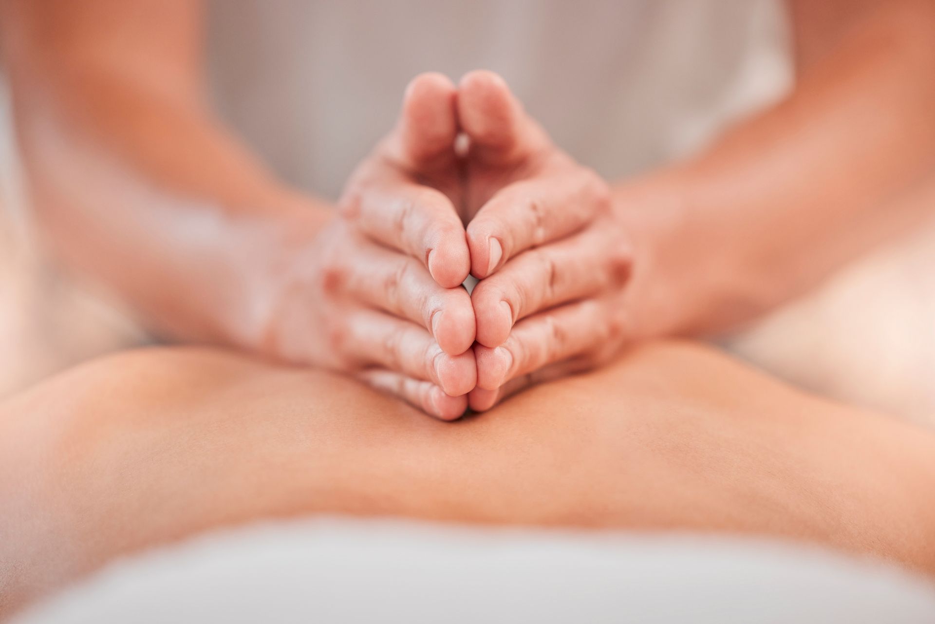 Close-up of hands gently pressing on a person’s bare back during a massage