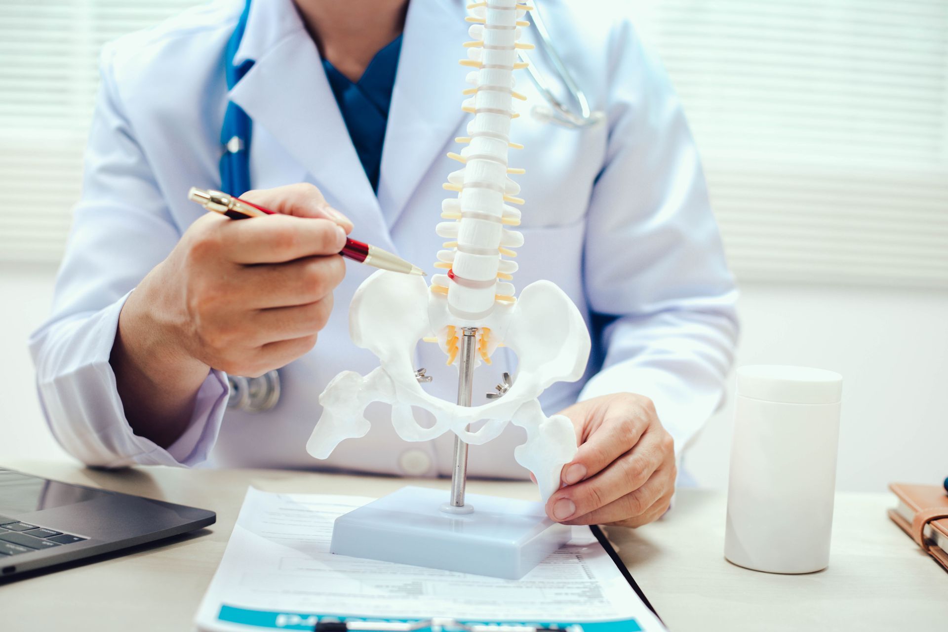 Doctor pointing to a spine model in a medical office