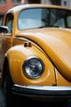 Nahaufnahme eines gelben Oldtimer-Volkswagen-Käfers mit Kotflügel und Scheinwerfer