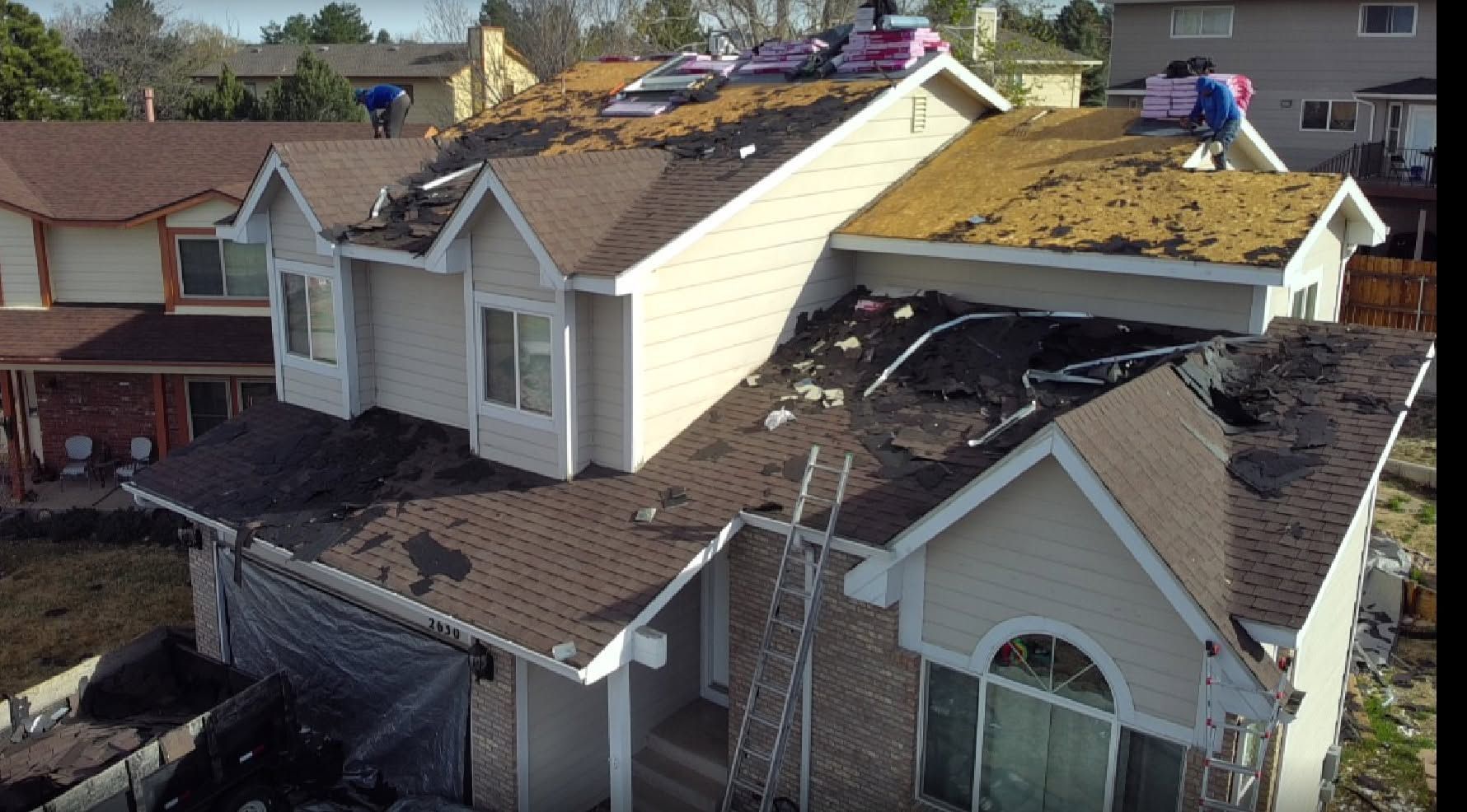 Damaged house roofs with tarps and debris after a storm, viewed from above