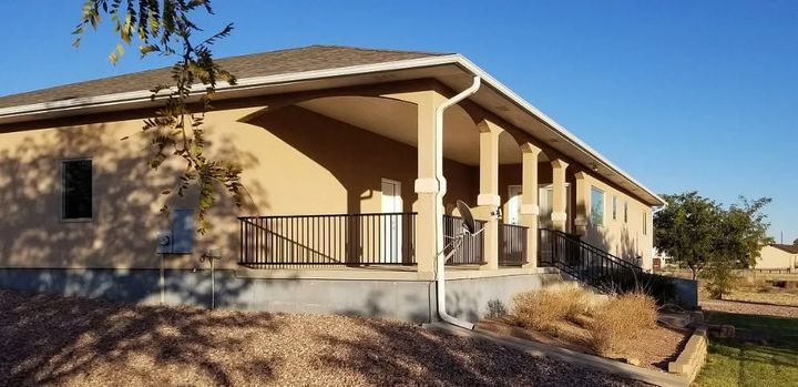 Single-story beige building with a covered porch and columns on a sunny day