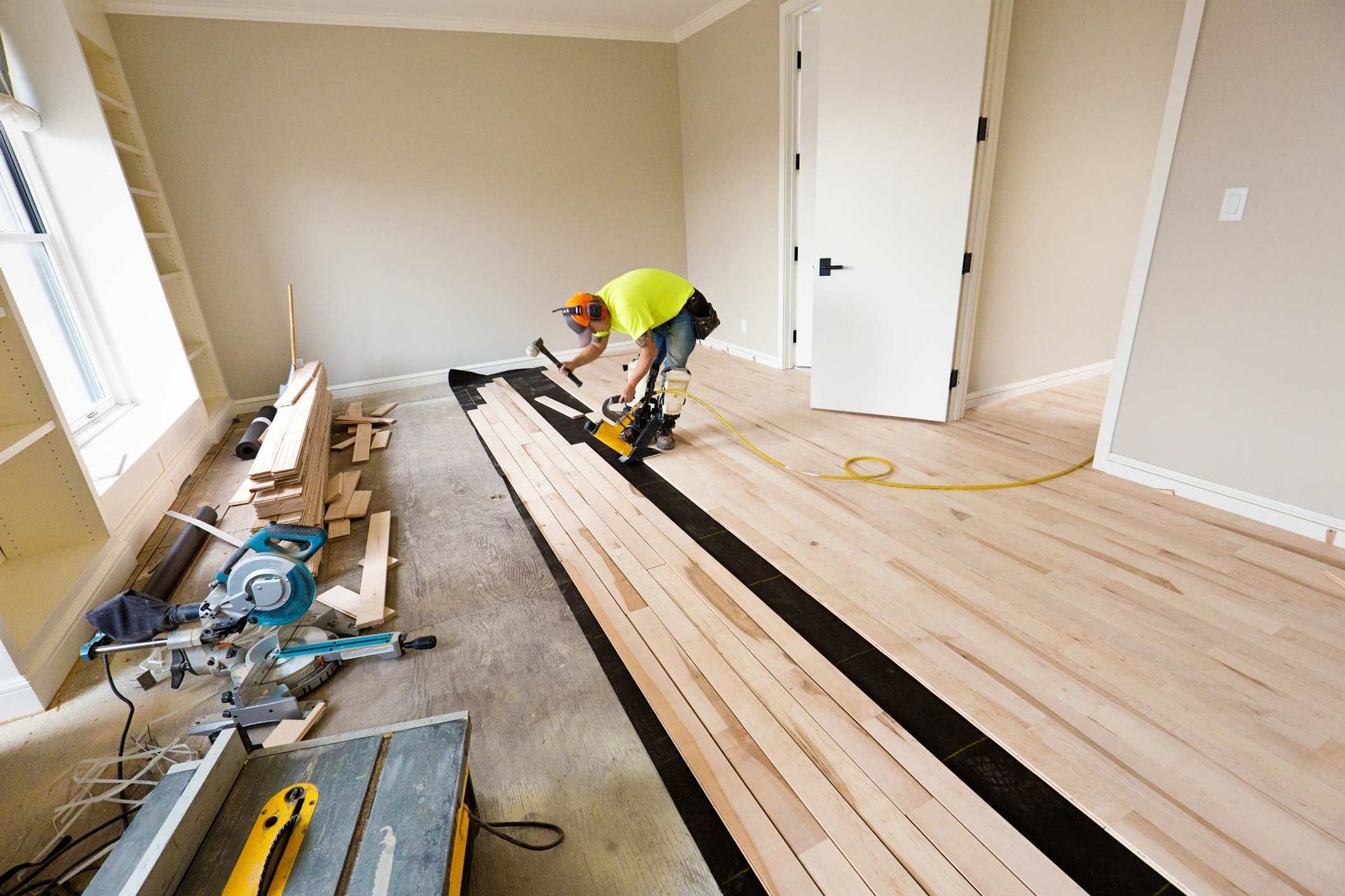 A Man Is Working on A Wooden Floor in An Empty Room | Gold Coast, QLD | Signature Sanding