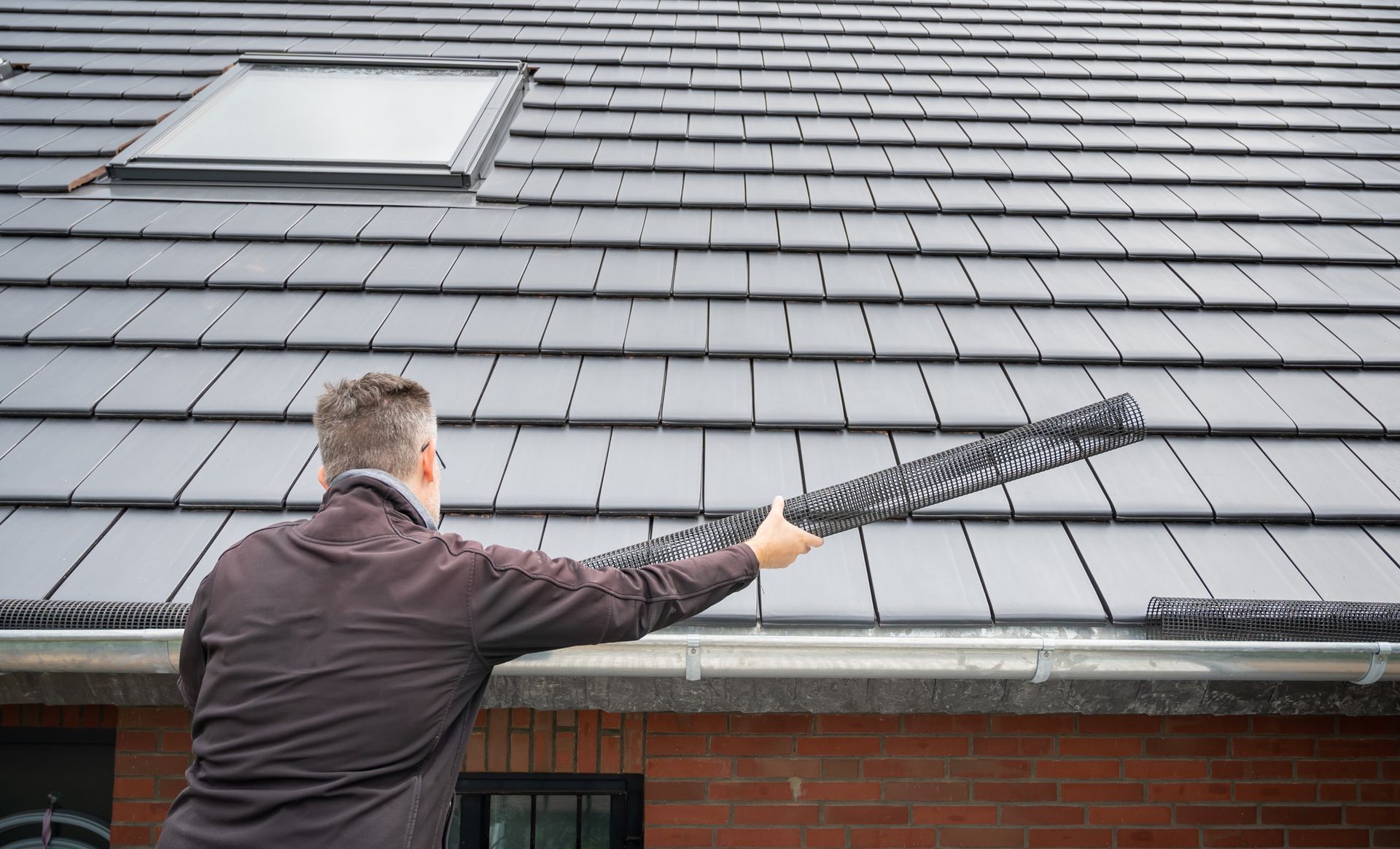 A man is cleaning a roof with a broom.