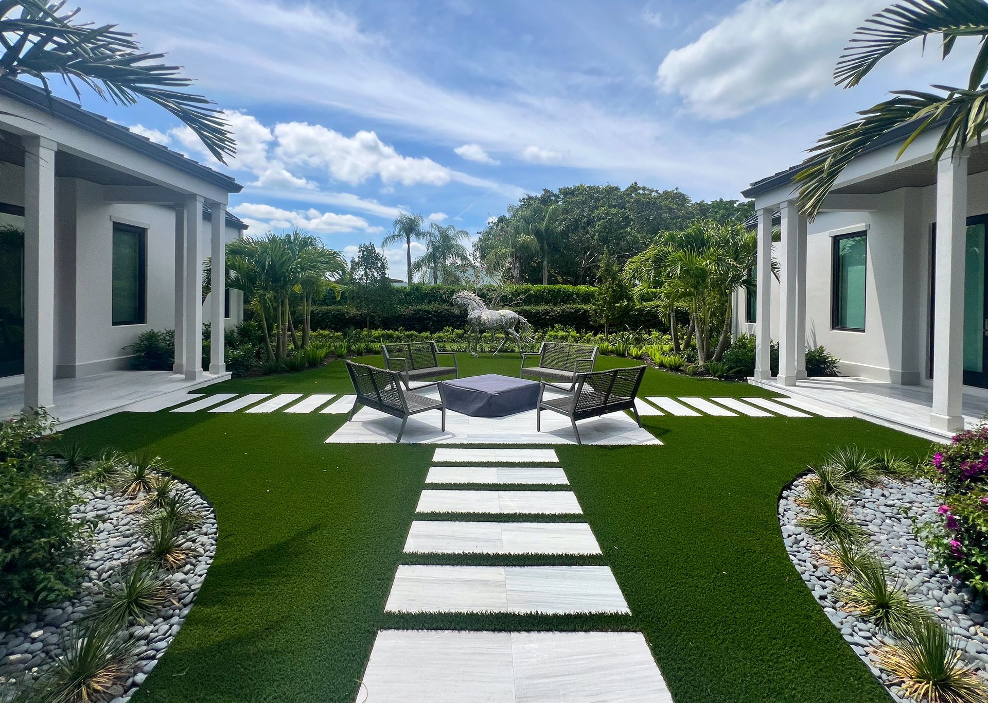 Wellington home with fire pit, outdoor seating, artificial turf, pavers, and palm trees.